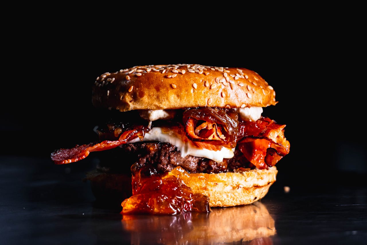 Home Close-up of a gourmet burger featuring bacon and sauce in vivid detail.
